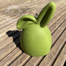 Load image into Gallery viewer, Jesmonite Bunny egg in an olive green colour shown on a wooden background.