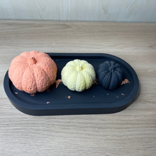 Load image into Gallery viewer, image shows a black oval tray with a copper coloured foil running length ways sat on top of the tray is 3 jesmonite pumpkins in black orange and yellow.