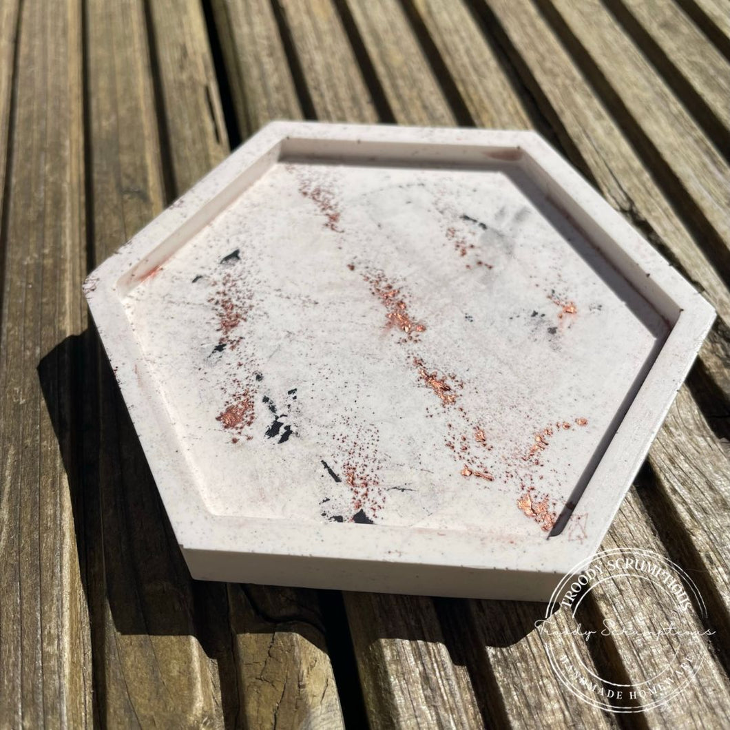 image shows a hexagon jesmonite trinket tray with a base colour of cream with black terazzo chips and a copper powder