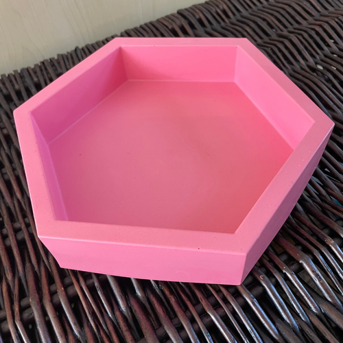 image shows a hexagon jesmonite tray in a neon pink colour with high sides and a smooth finish
