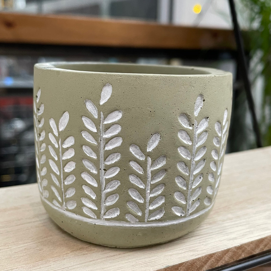 image shows a small plant pot in light green with a leaf design handpainted in white.